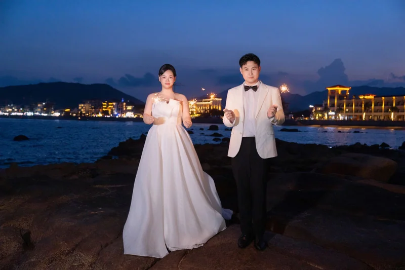 夜幕海岸上手持仙女棒的新人